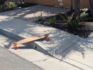 A longboard on a sidewalk curb